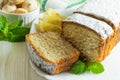 Slices of biscuit cake with powdered sugar, decorated with mint leaves, lemon slices and small cookies, on a white wooden table Royalty Free Stock Photo