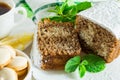 Slices of biscuit cake, a ÃÂup of tea with lemon, small cookies and mint leaves on a white wooden table Royalty Free Stock Photo