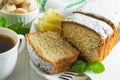 Slices of biscuit cake, a ÃÂup of tea and small cookies on a white wooden table