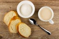 Slices of bread, bowl with sugar, cup with fermented baked milk, spoon on wooden table. Top view Royalty Free Stock Photo