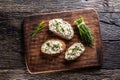 Slices of bread with a cottage cheese spread, freshly cut chives, and a bunch of chive aside placed on a dark brown Royalty Free Stock Photo