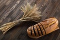 Slices of bread on a cutting board and ears of wheat on the wood Royalty Free Stock Photo