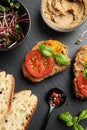 Slices of bread with delicious pate, tomatoes and basil on black table, flat lay Royalty Free Stock Photo