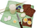 Slices of bread with eggs, glass of milk, rye and bluebell flower on checkered table-napkin