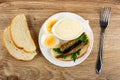 Slices of bread, halves of eggs, sandwich with sprats and parsley, bowl with mayonnaise in plate, fork on table. Top view Royalty Free Stock Photo