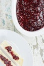 Slices of bread on plate and raspberry marmalade in porcelain cookware on rustic table