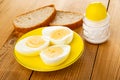 Slices of bread, saucer with halves of boiled eggs, salt on wooden table