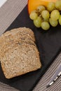 Slices of brown bread, grapes and gouda cheese on slate board Royalty Free Stock Photo