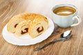 Slices of bun with jam filling in white plate, blue cup with black coffee, spoon on wooden table Royalty Free Stock Photo