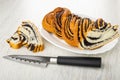 Slices of bun with poppy, piece of bun in dish, knife on wooden table