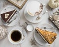 Slices of cake with caramel and chocolate, fresh coffee, milk, vintage spoons, frame, book, pumpkin and meringue. Royalty Free Stock Photo