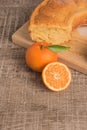 Slices of clementine cake with powdered sugar topping. Cake on a board with fresh clementines on wooden board