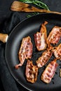 Slices of crispy hot fried cooked bacon. Farm organic meat. Black background. Top view Royalty Free Stock Photo