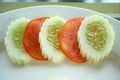 Slices of cucumbers and tomatoes on edge of white plate. Royalty Free Stock Photo