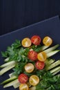 Slices of cucumbers and tomatoes on a slate on a black wooden table. Royalty Free Stock Photo