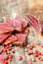 Slices of cured meet and pepper on wooden table Royalty Free Stock Photo