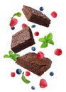 Slices of delicious chocolate brownie with fresh berries and mint flying on white background Royalty Free Stock Photo