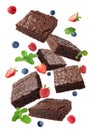 Slices of delicious chocolate brownie with fresh berries and mint flying on white background Royalty Free Stock Photo