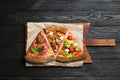 Slices of different delicious pizzas on black wooden table Royalty Free Stock Photo