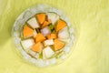 Slices different melon with ice on plate around green background. tasty sweet exotic fruit. flat lay