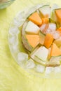 Slices different melon with ice on plate around green background. tasty sweet exotic fruit. flat lay