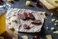 Slices of dried meat, chopped Spanish hard cheese manchego on wooden cut, sliced Italian pecorino toscano, red grapes Royalty Free Stock Photo
