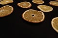 Slices of dried oranges lay in pattern at black background, copy space,