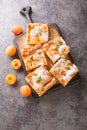 Slices of fresh apricot iced sponge cake with fruits closeup on the wooden board. Vertical top view Royalty Free Stock Photo