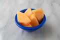 Slices of fresh cut cantaloupe in a blue bowl on marble