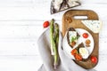 Slices of dark bread with blue cheese, eggs, tomatoes on wooden cutting board decorated with asparagus. Flat lay, top view Royalty Free Stock Photo