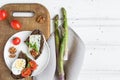 Slices of dark bread with blue cheese, eggs, tomatoes on wooden cutting board decorated with asparagus. Flat lay, top view Royalty Free Stock Photo