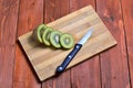 Slices of fresh kiwi fruit and a knife on a wooden background. Royalty Free Stock Photo