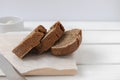 Slices of fresh rye bread on wooden board on white table Royalty Free Stock Photo