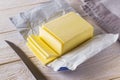 Slices of fresh yellow butter cut off from a just opened pack and knife on a white wooden table. Dairy. Sandwich butter. Natural Royalty Free Stock Photo