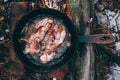 Slices of fried bacon in a pan. Food in a forest camp. Cooking on fire. Picnic in the nature. Grilled food on nature Royalty Free Stock Photo