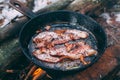 Slices of fried bacon in a pan. Food in a forest camp. Cooking on fire. Picnic in the nature. Grilled food on nature Royalty Free Stock Photo