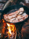 Slices of fried bacon in a pan. Food in a forest camp. Cooking on fire. Picnic in the nature. Grilled food on nature Royalty Free Stock Photo