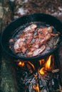 Slices of fried bacon in a pan. Food in a forest camp. Cooking on fire. Picnic in the nature. Grilled food on nature Royalty Free Stock Photo