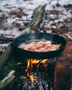 Slices of fried bacon in a pan. Food in a forest camp. Cooking on fire. Picnic in the nature. Grilled food on nature Royalty Free Stock Photo