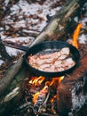 Slices of fried bacon in a pan. Food in a forest camp. Cooking on fire. Picnic in the nature. Grilled food on nature Royalty Free Stock Photo