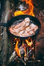 Slices of fried bacon in a pan. Food in a forest camp. Cooking on fire. Picnic in the nature. Grilled food on nature Royalty Free Stock Photo