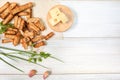 Slices of fried croutons with sour cream sauce, red pepper, cheese and garlic cloves close up on a white wooden boards