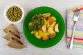 Slices of fried potatoes in plate with dill, bowl with green peas, bread, fork on napkin on table. Top view Royalty Free Stock Photo