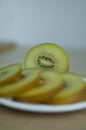 Slices of golden kiwi with yellow pulp on white plate on the kitchen. Exotic fruits, healthy eating concept Royalty Free Stock Photo