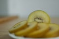 Slices of golden kiwi with yellow pulp on white plate on the kitchen. Exotic fruits, healthy eating concept Royalty Free Stock Photo