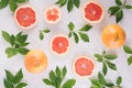 Slices grapefruit and green leaves on soft white wooden background, pattern, top view.