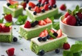 Slices of green cakes with fruit as garnish. hand in frame. Cake potong