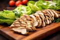 slices of grilled chicken laying on top of fresh romaine lettuce