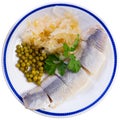 Tasty slices herring fish with canned green peas, pickled cabbage, decorated by onion rings served on plate Royalty Free Stock Photo