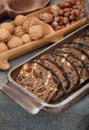 Home-baked bread with dried fruits and nuts in a wooden tray, walnuts and hazelnuts in the backgroun, rustic style food background